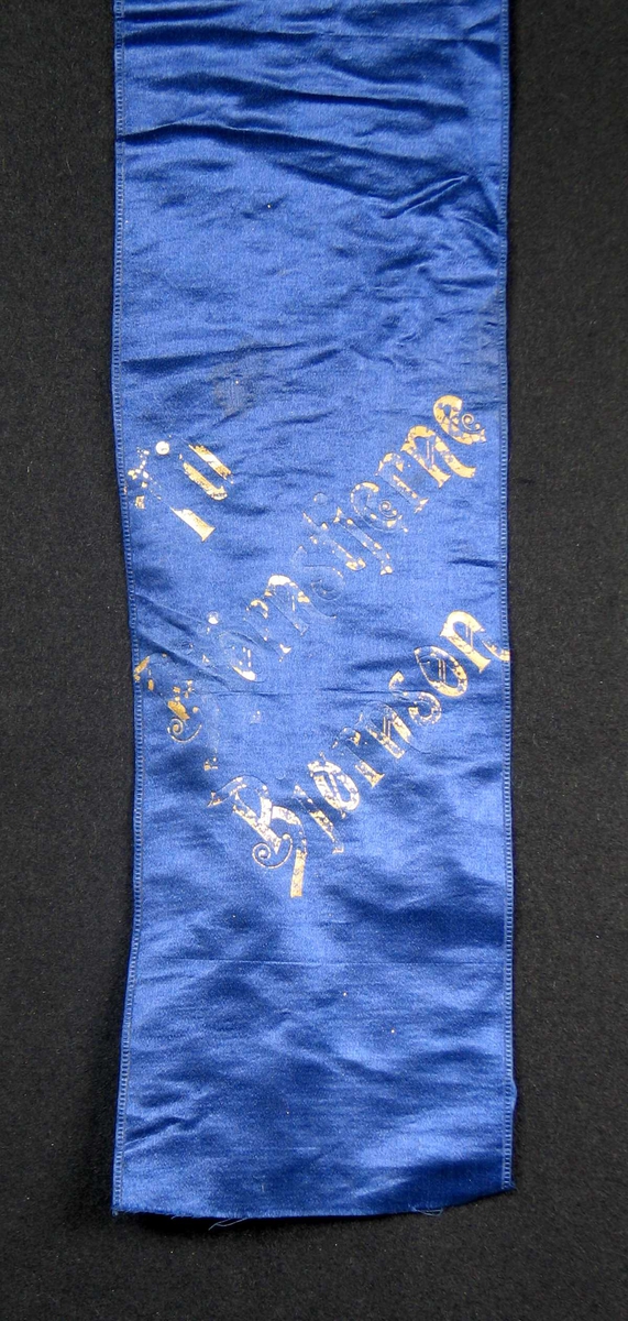 Begravelsessløyfe i blå silke med tekst i gull.