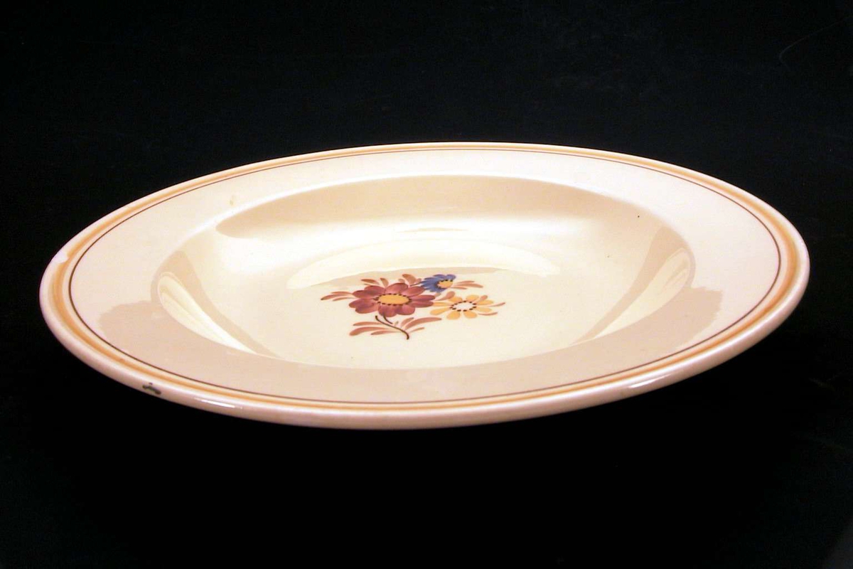 Gul tallerken med blomsterdekor på midten og med en oker og en brun linje langs kanten. Det er skår i kanten av tallerkenen.