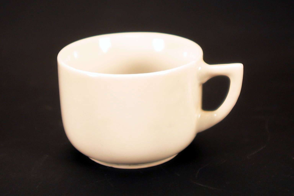 Liten, hvit kopp uten dekor. Den er stemplet 'Made in Japan', sammen med et merke med bokstavene OTO (eller OTC). 