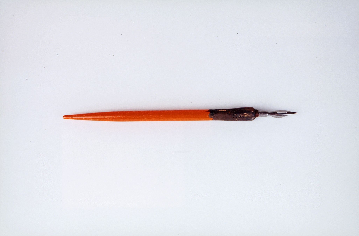 Pennskaft i tre med metall pennsplitt.
Orange og svart, det orange belegget har sprekker.