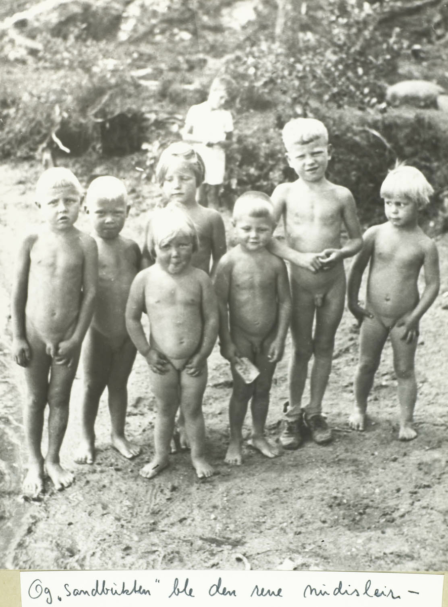 Åtte barn på badestrand, hvorav 7 nakne