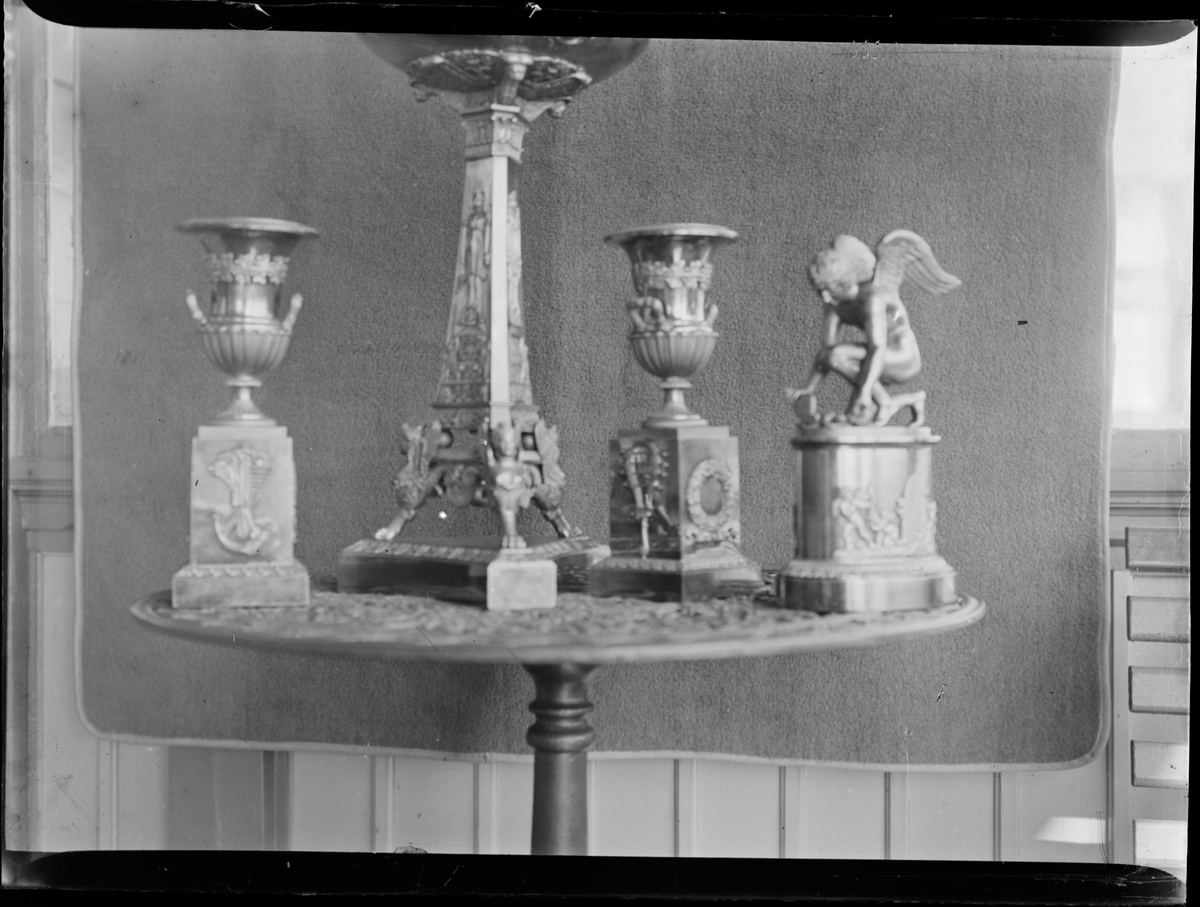 Vaser og en liten atatuett av Amor på et rundt bord.