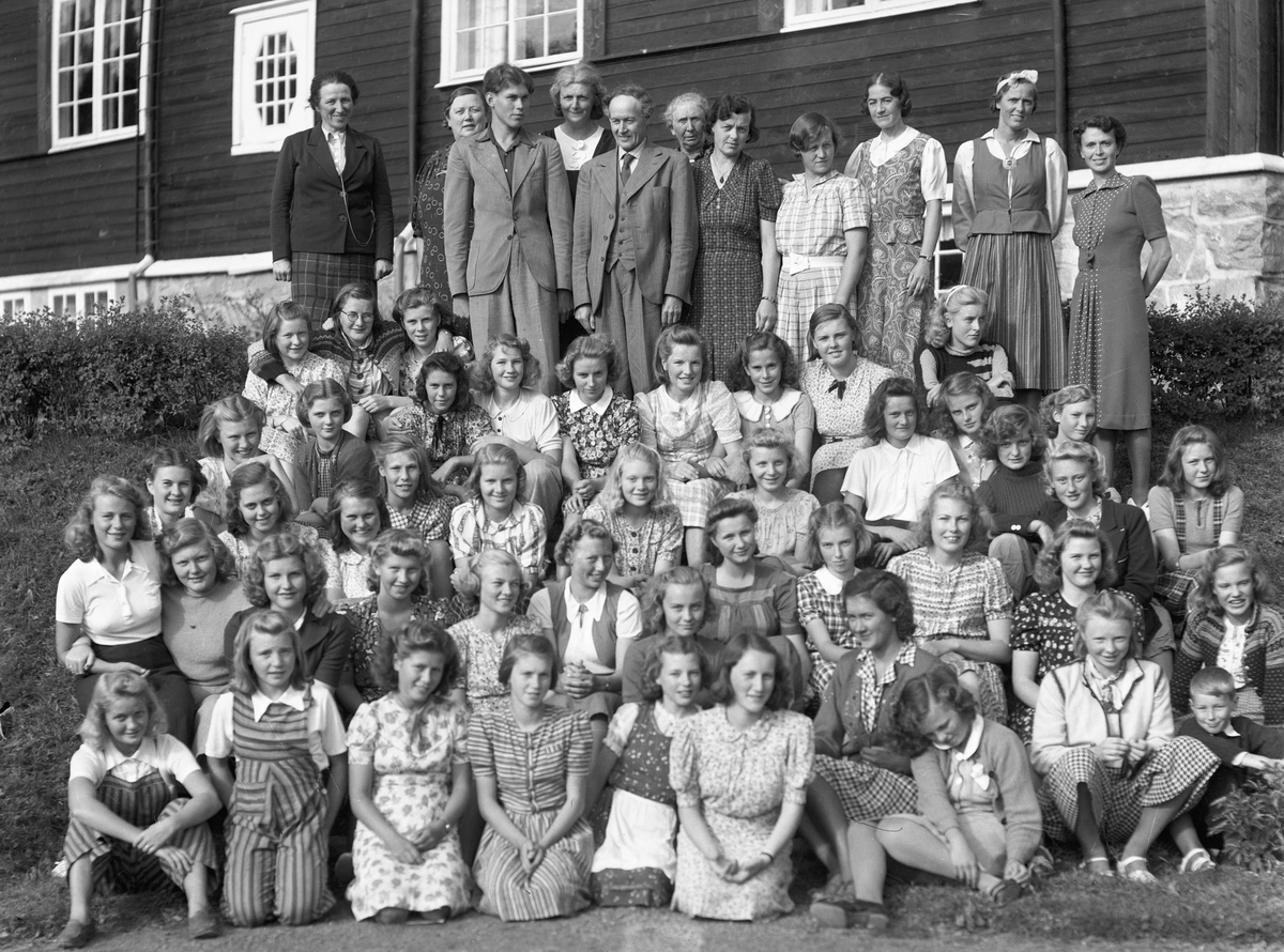 Gruppe voksne og ungdommer utenfor Eidsvoll Landsgymnas. Kan være rektor Jacob Voss med dress og slips bakerst. Han var rektor fra 1922 og fram til 1945.