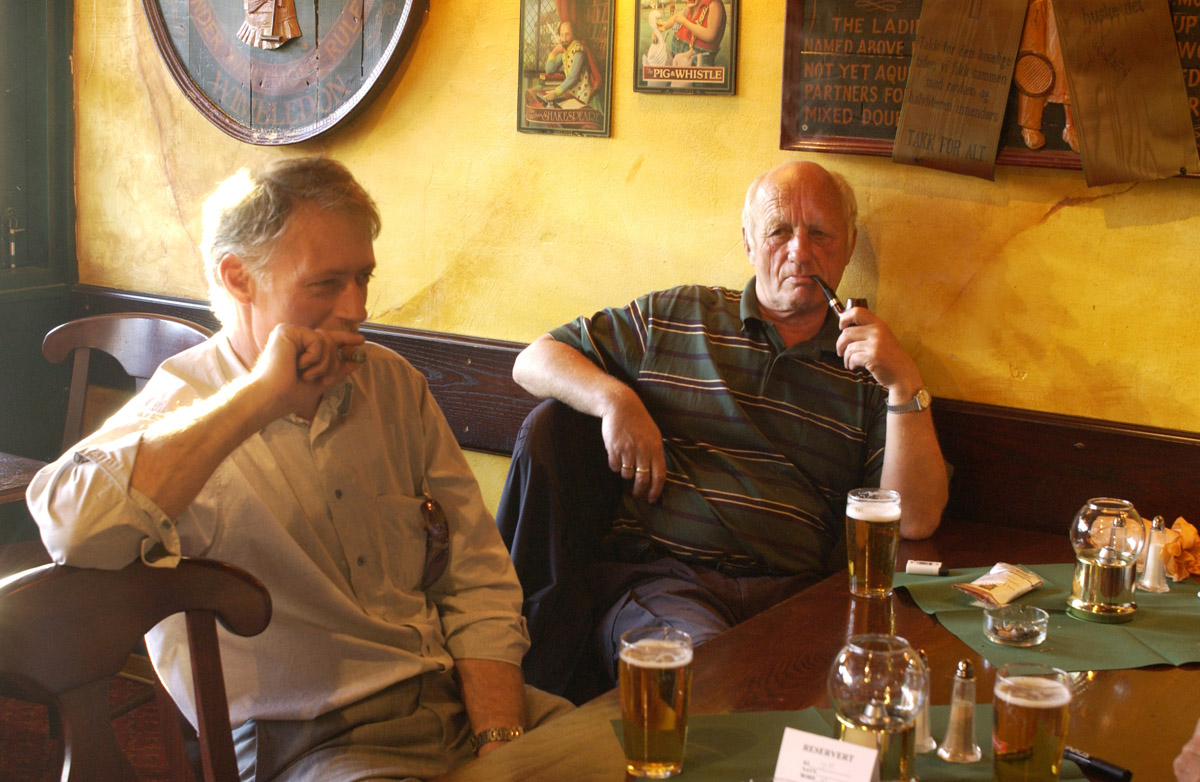 2 menn ved et bord med sigar og tobakkspung. Bowler & Spisepub.