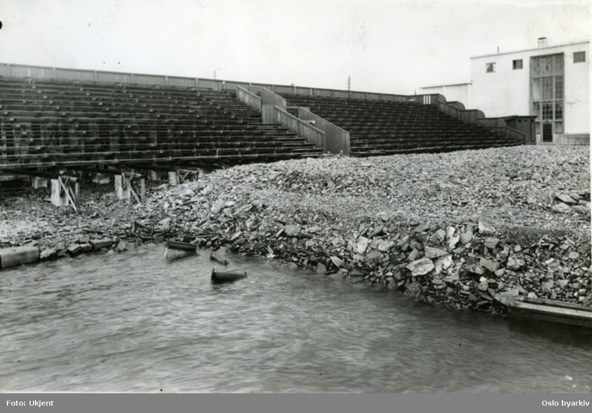 Svømmestadion 1. Svømmestadion som ble åpnet i 1925 og som i 1932 måtte rives på grunn av bryggeutvidelsen og utfylling av Filipstadbukta. Rester av tribunen og fyllmasse for bryggeområdet. I bakgrunnen ses lagerbygningen til bananmodneriet.