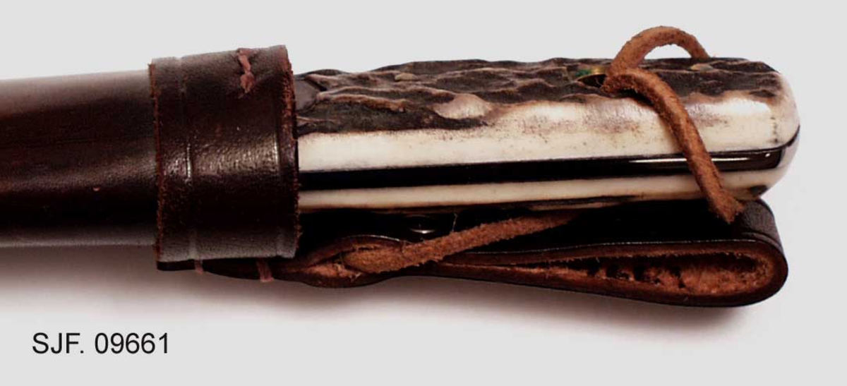 Kniven sitter fast i slira ved at et hull i knivskaftet hvor det er tredd ei reim som er festet til slira. 