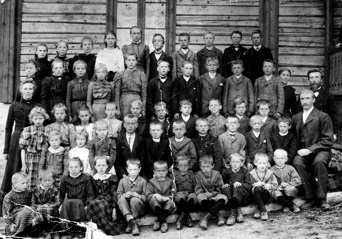 Stor gruppe elever fra Evenrud skole, Helgøya. Lærer Ole Gunerius Hansen (1847-1919) med skjegg, lærer Kristine Olsen f.1874 til venstre.
