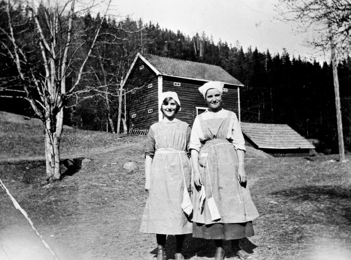 Alvhild Raknerud (f 1905) og Ingrid Esther Røste (f 1906) foran stabburet på Kjelsrud, Helgøya.