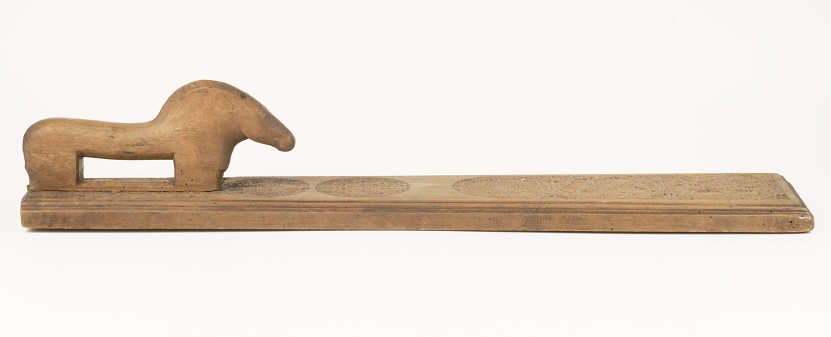 Mangletreets håndtak er utformet som en hest .
Håndtaksidens overside på mangletreet har til dekor :
Utskåret karveskurd over helle oversiden på mangletreet .