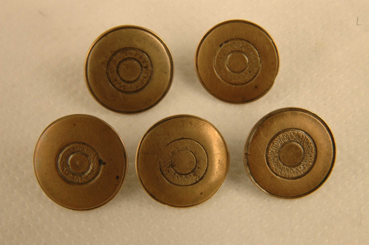 Fem tilnærmet like runde, støpte knapper med gravert sirkelmotiv.
