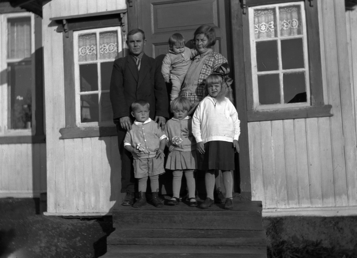 Familie på trappa ved inngangen til et hus. 
Bildet er tatt på trappa i Vestby i Løten. Personene er Peder og Olea Talbak (Rasch) og barna deres. Den eldste jenta hette Hjørdis. Barnet på armen hette Gunnar Jostein. Begge disse barna døde så tidlig, som ca. bare 10 og 2 år gamle. Tvillingene foran er Sverre Talbak og Oddveig Holmen. 
