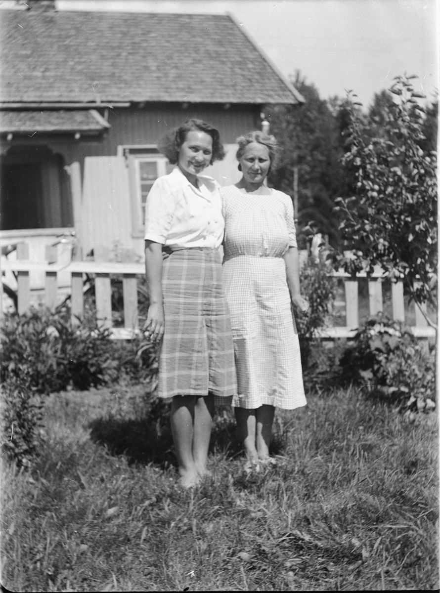 To kvinner i en hage med gjerde. 