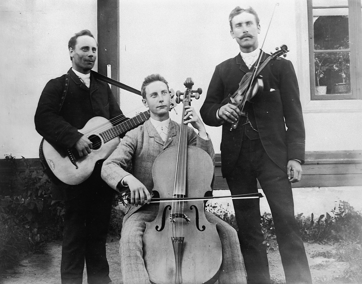 3 ukjente musikere med instrumenter. Gitar, cello og fiolin.