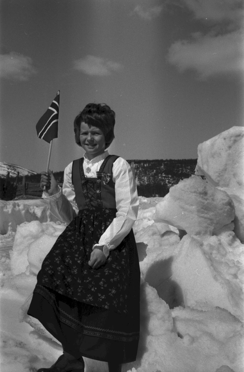 Tolga, Øversjødalen, 17. mai, Jente pyntet til fest sittende på en snøhaug, Norske flagg, Bunad