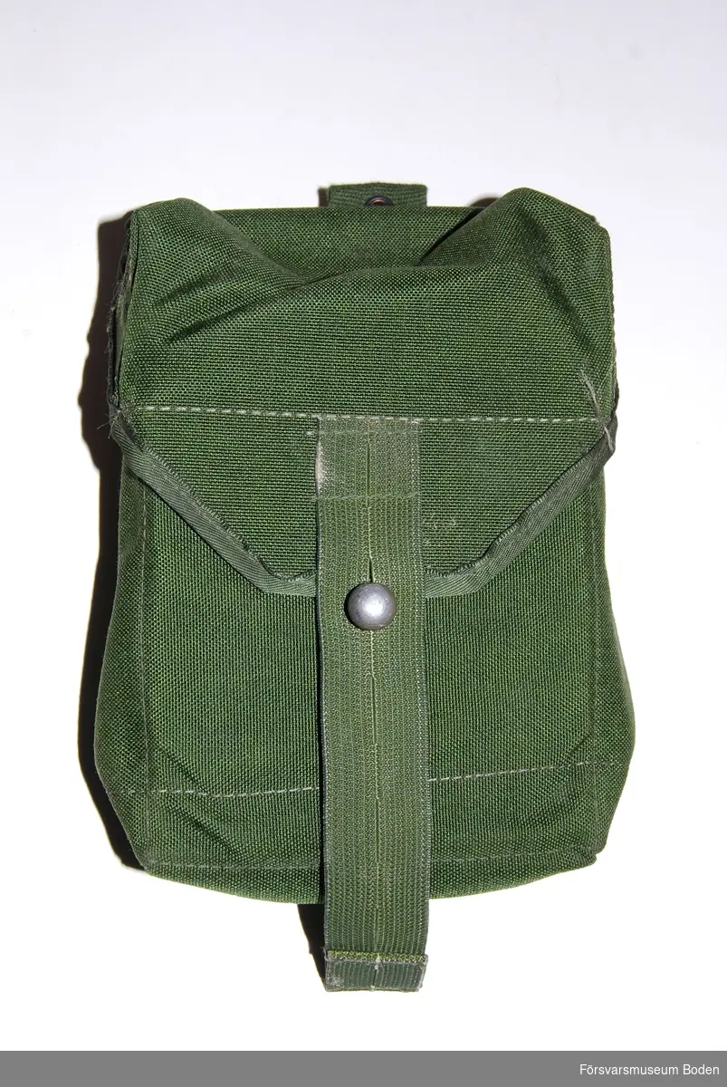 Av grönt syntettyg med metallhakar för bältet på baksidan. Lockets slejf har två valfria knapphål. Avsedd för fyra st AK47-magasin eller fem M16/M4-magasin.