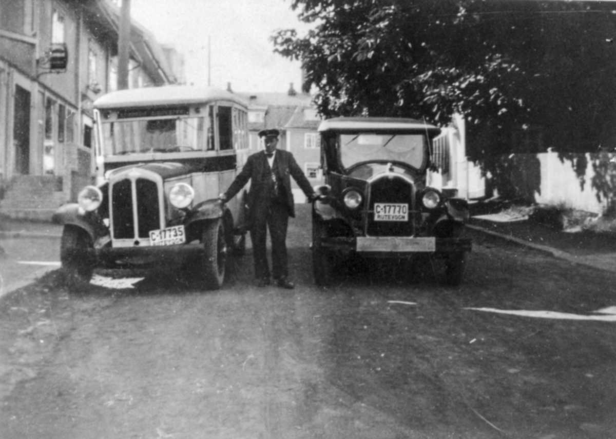 Mann mellom en buss og en bil. Begge med skilt «Rutevogn». Bussen med skiltnr. C-17735, bilen med nr. C-17770.
24.03.2014:
Bilen til høyre er en 28 mod. Buick 7 seter C-17770, som Buss-Olsen, (stående i midten) begynte å kjøre i rute mellom Gullverket og Eidsvoll st i 1928. I 1931 fikk han levert den første ordentlige bussen, en Reo 1931 mod, bygget ved Ygaard & Fosserud karosseriverksted på Styri i Eidsvoll, C-17735, 14 seter + gods (og det kunne være mye rart). Her ser vi Buss-Olsen stående  mellom "den gamle og nye tid" fotografert i Sundet.
Skrevet av: Hans Fredrik Hansen