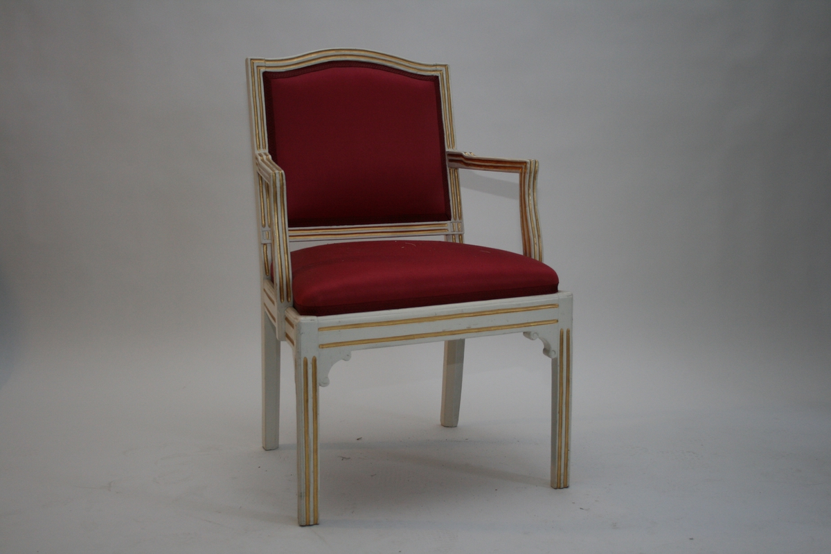 En av to stoler, m. armlener.
Empire, hvite med gull, rødt silketrekk.
Profilerte hjørneklosser.