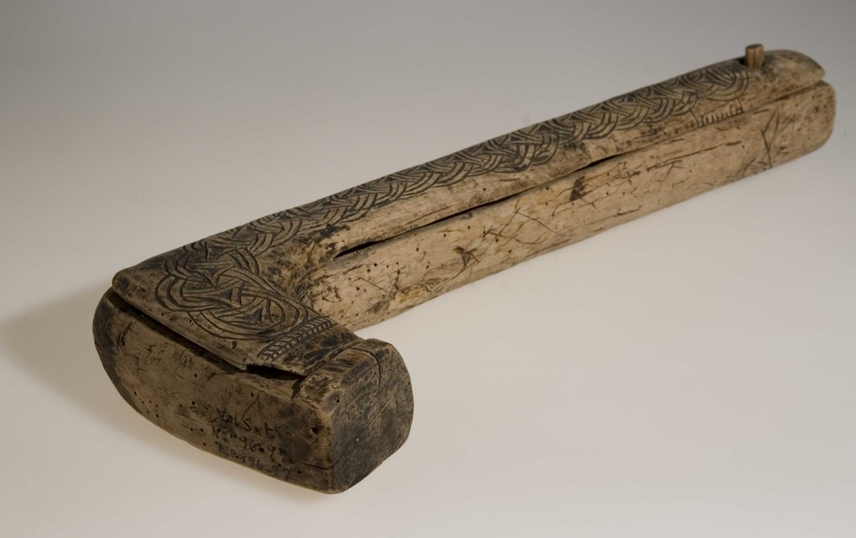 Skrin laget fra et trestykke tatt fra grenfeste. Lokket er skåret tangentielt fra trestykket og bunndelen er siden urholket. Lokket er festet i en dømling ved enden av den lange delen. Skrinet er dekorert med skurd kjedemønster. Dybdedelene i mønstret er forsterket med sot (kolrosingteknikk). Ellers ubehandlet treflater.