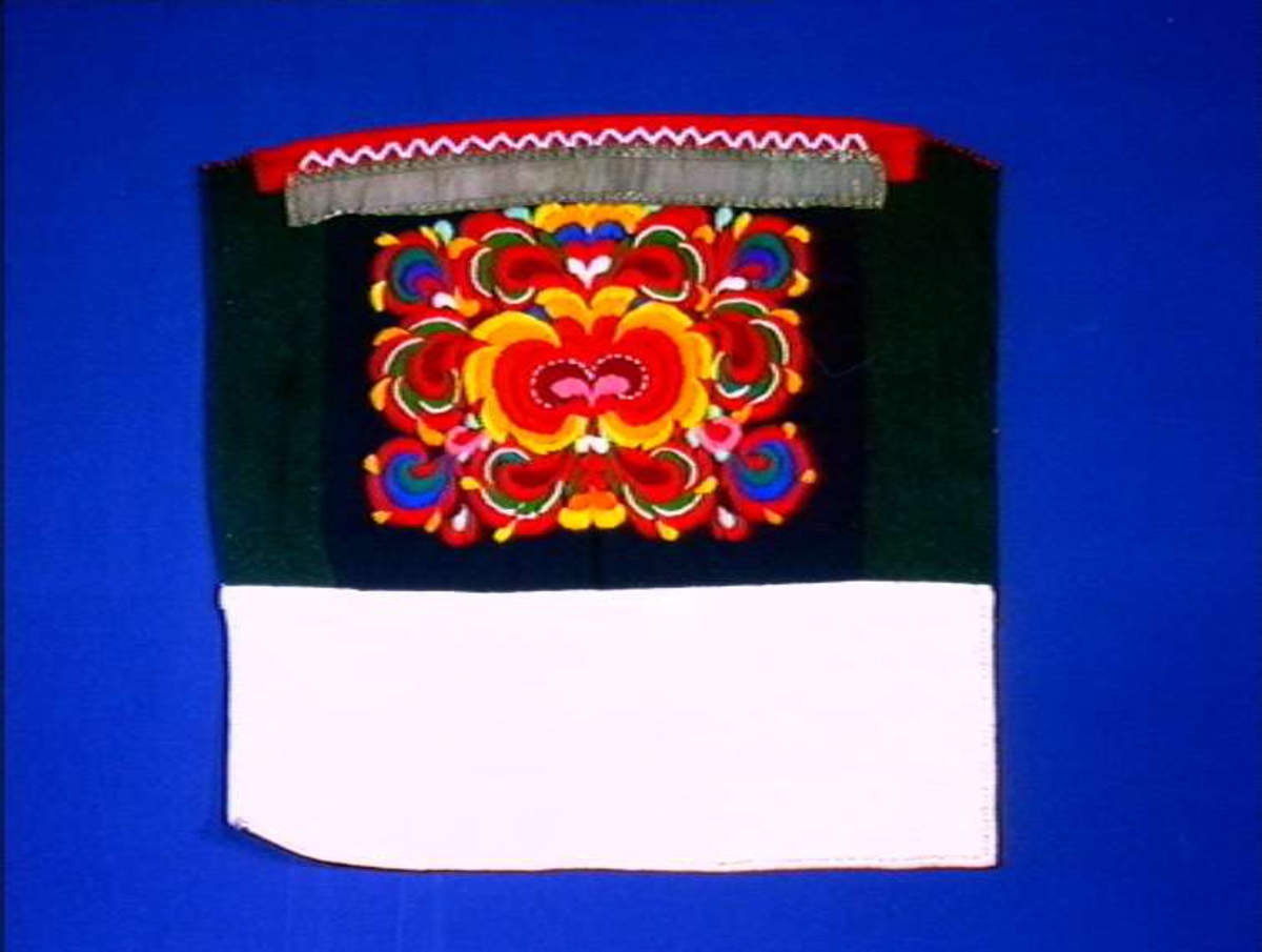 Brystklut i ull med dekor av rossøm, metallbånd og glassperler.