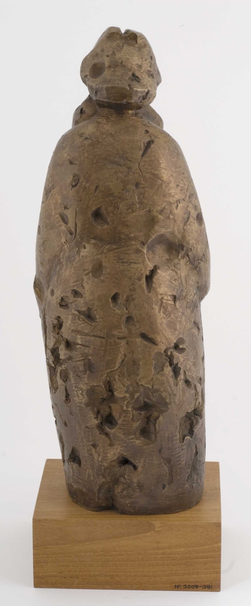 Metallskulptur på tresokkel, plakett på sokkel.