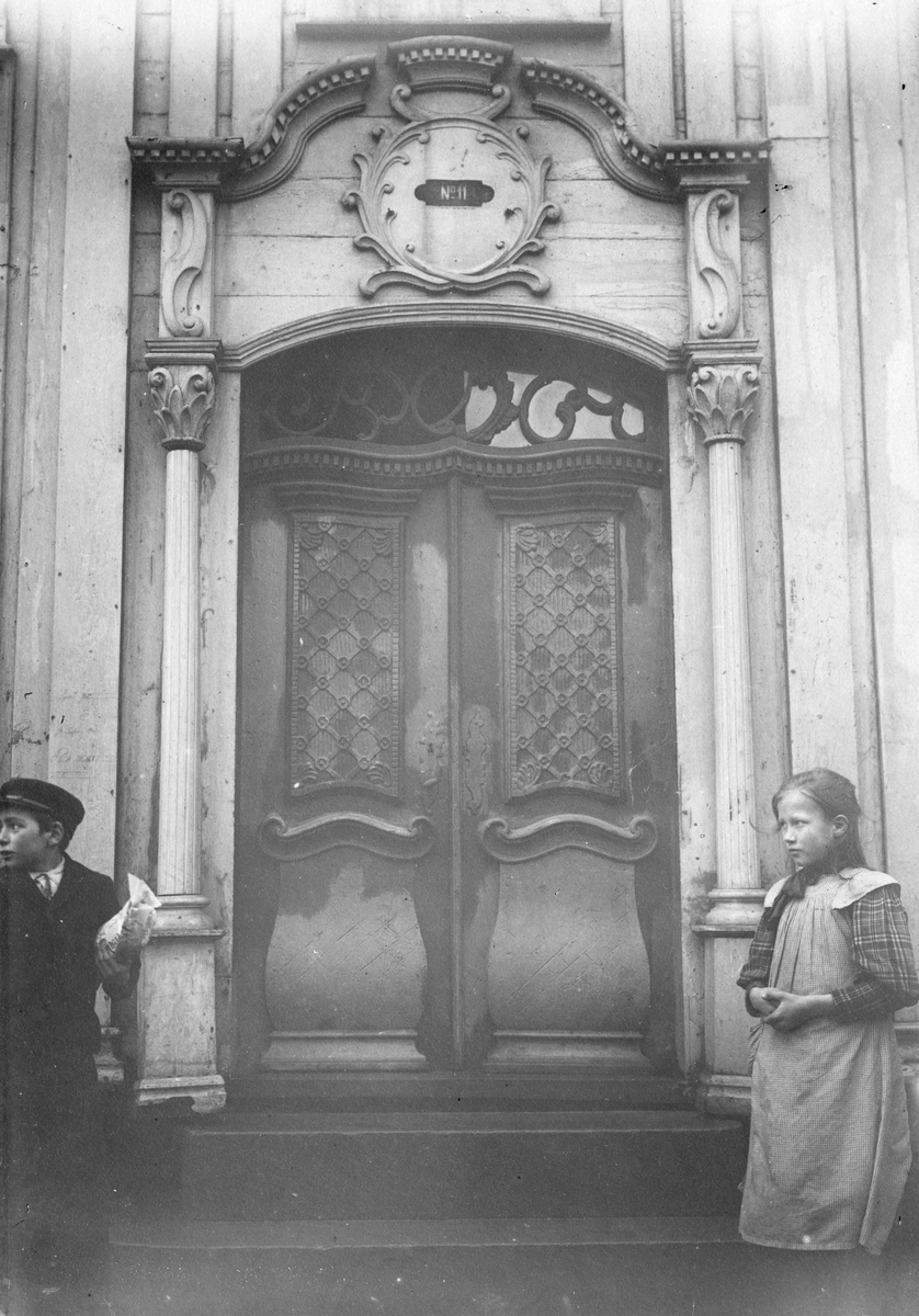 Inngangsparti med portal på Brodtkorbgården fra 1785 i Kristiansund i Møre og Romsdal. En gutt og en jente står ved trappen. Fotografert i 1908.
 Lunds nr.15.