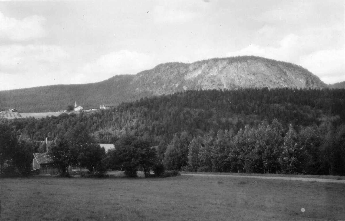 Svangstrand, Lier, Buskerud. 1930. Oversiktsbilde. Landskap med dyrket mark. Gårdsanlegg. Kirke. Fjell i bakgrunnen.