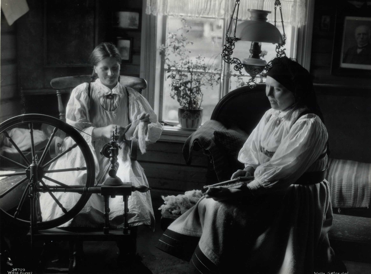 To kvinner karder og spinner i en stue. Valle, Setesdal, Aust-Agder, antagelig 1929.
