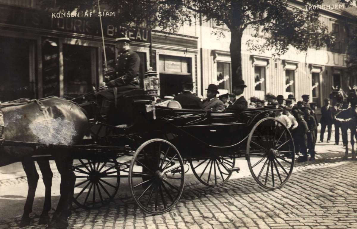 Postkort. Kongen av Siam sitter i karet i en gate i Trondheim. Datert 15.07.1907.