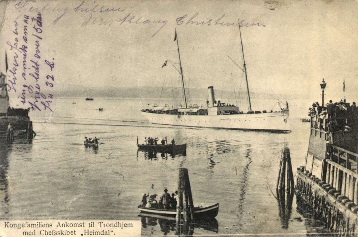 Postkort. Mange mennesker på bryggen og i båter da kongeskipet "Heimdal" ankommer Trondheim. Stemplet 23.07.1906.