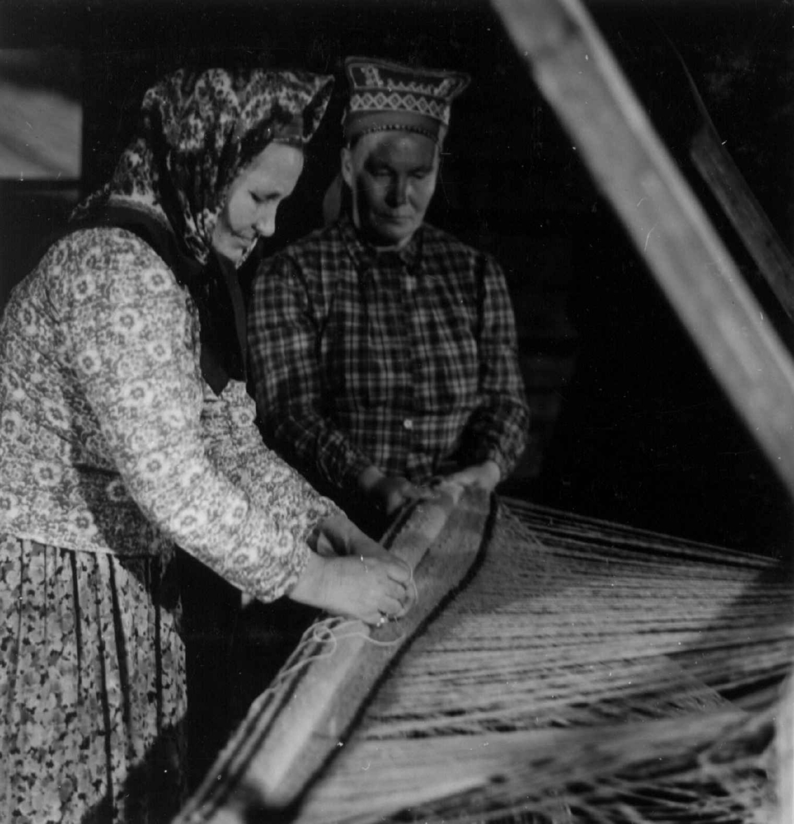 Greneveving. Skoltesamene Darja og Naska Moshnikov demonstrerer grenveveing på Föllisöen, Helsinki Universitet, Finland 1955. 26. Vevnaden vindes opp på bommen. 