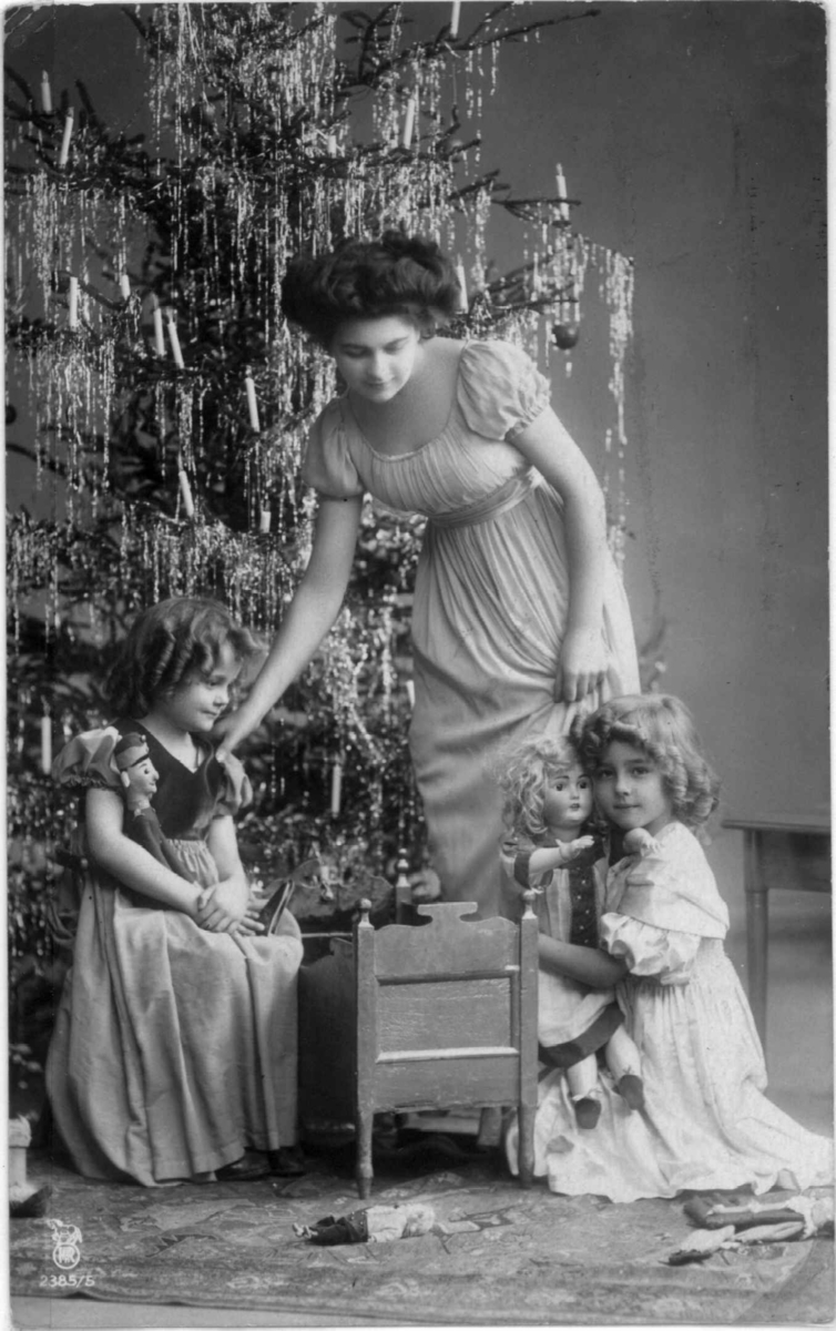 Postkort, stemplet 1909. Kvinne og barn foran juletre.