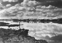 Avfotografert postkort. En mann står ved Ørtevann på Hardang