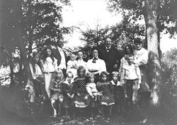 Familiegruppe oppstilt mellom trær.