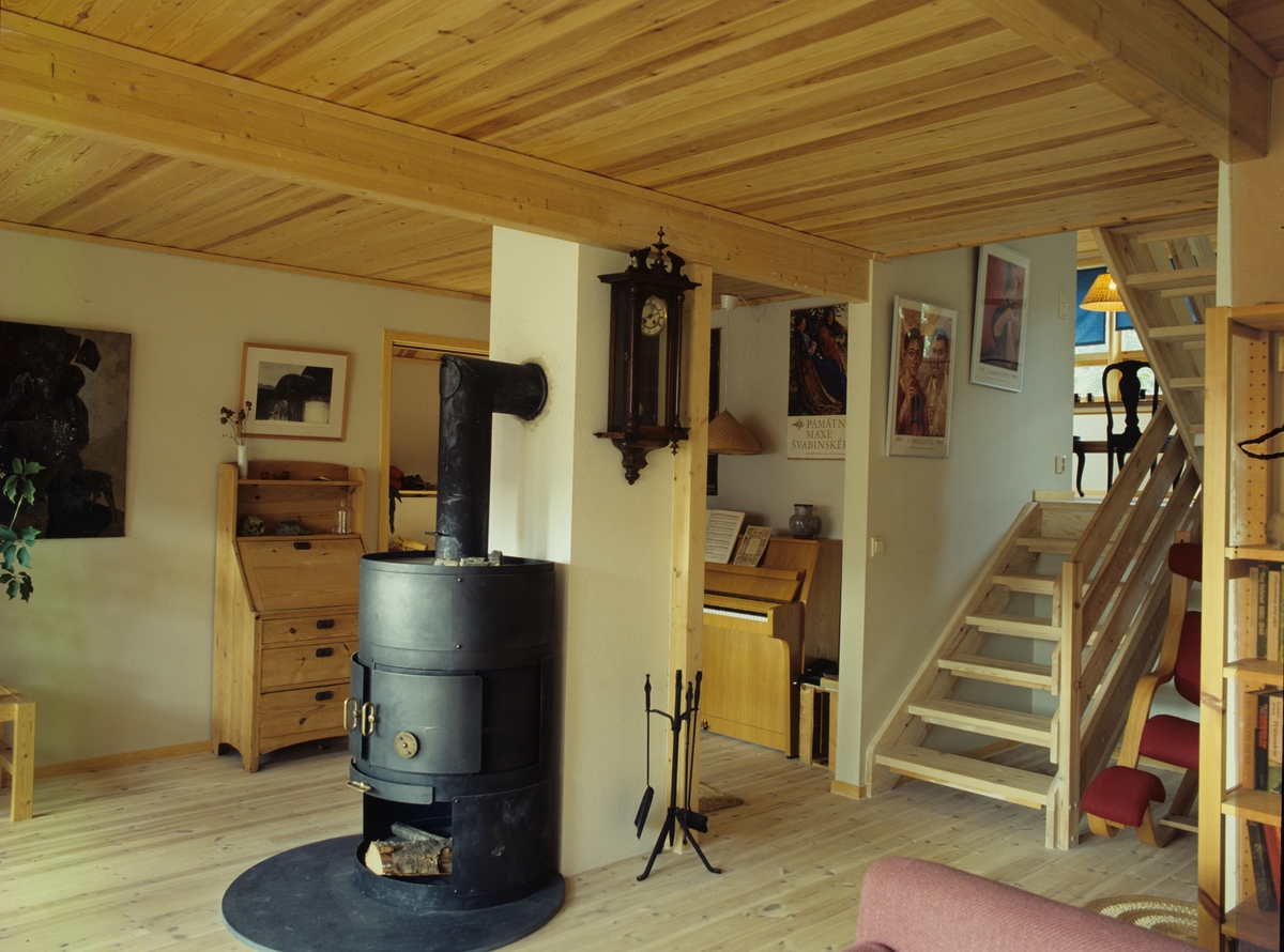 En trapp kommer ned fra etasjen over, hvor det er en peis som står sentralt i rommet, i et av husene i Hadlabrekko Burettslag ved Lervik på Stord. Illustrasjonbilde fra Bonytt 1987.