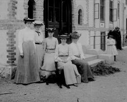 Gruppeportrett, gruppe kvinner utenfor inngangen til murbygn