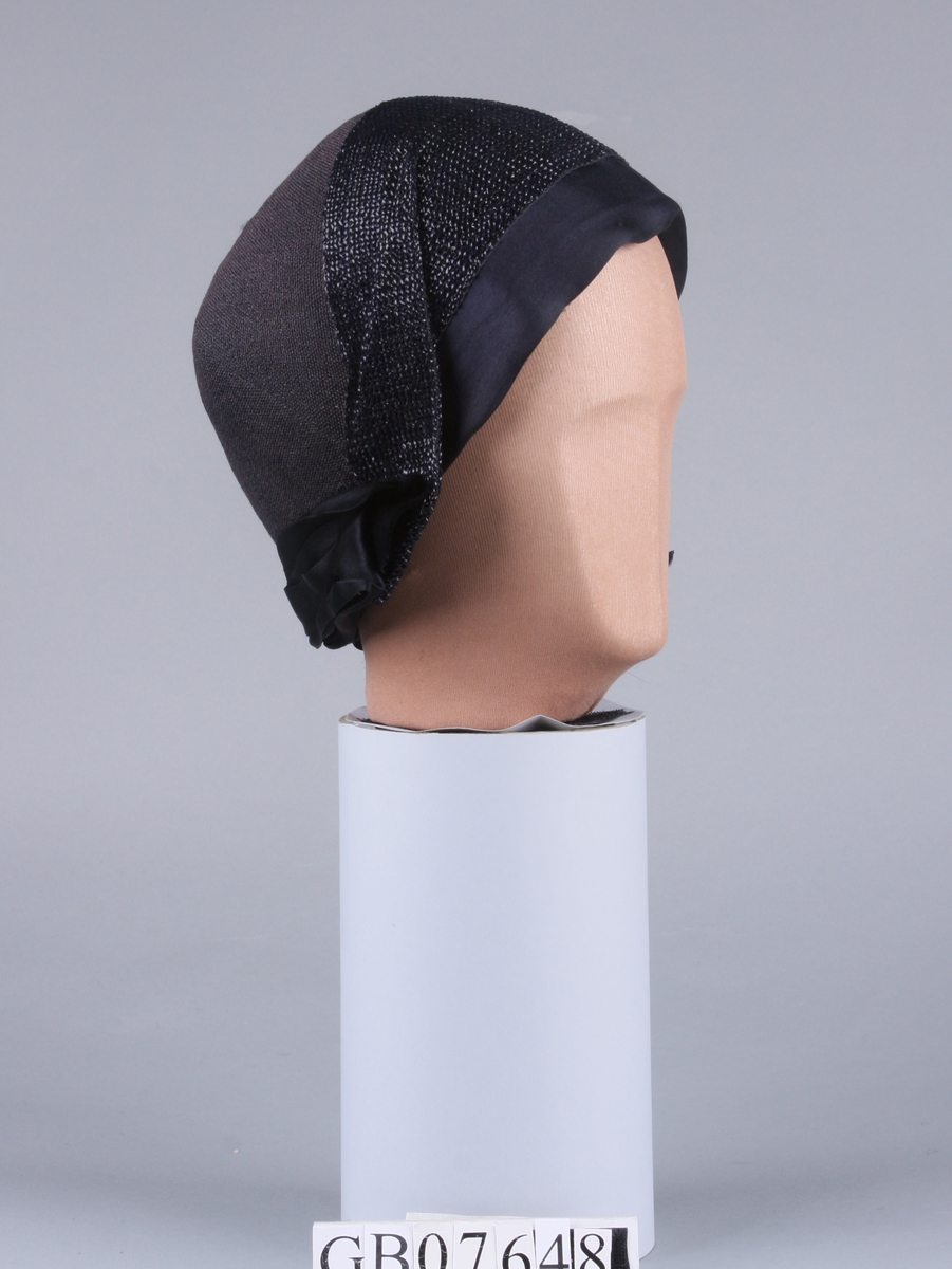 Bløt hatt med silkesløyfe bak. Pyntet med et 10 cm bredt vevet bånd av stråmateriale rundt hele kanten.