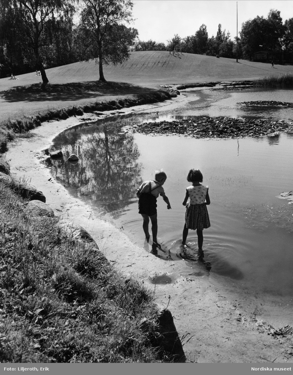 Två barn en pojke och en flicka som leker vid en damm i en av Malmös parker, troligen Beijers park.