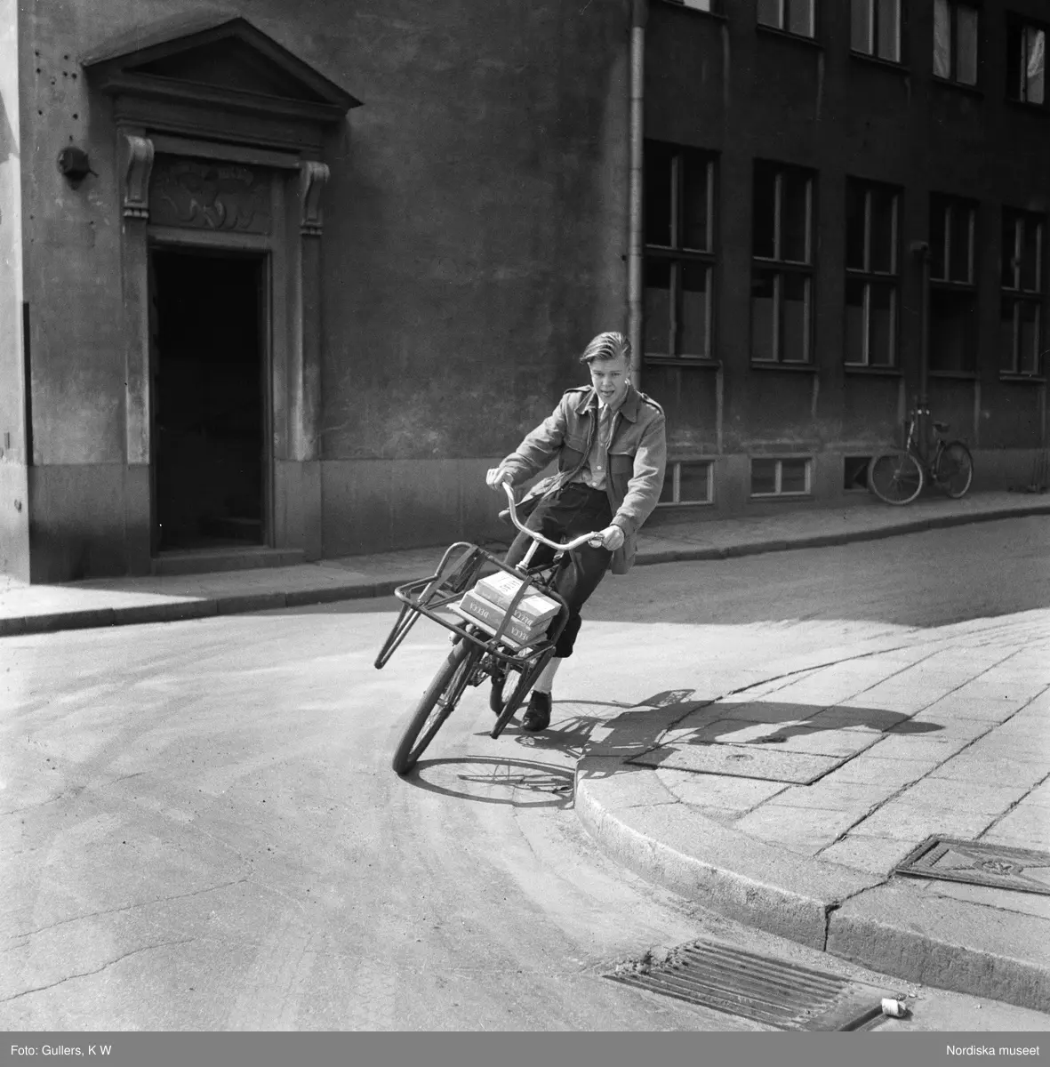 Cykelbud i Stockholm. Pojke cyklar p&aring; en stadsgata, v&auml;nstertrafik. P&aring; paketh&aring;llaren ligger paket.