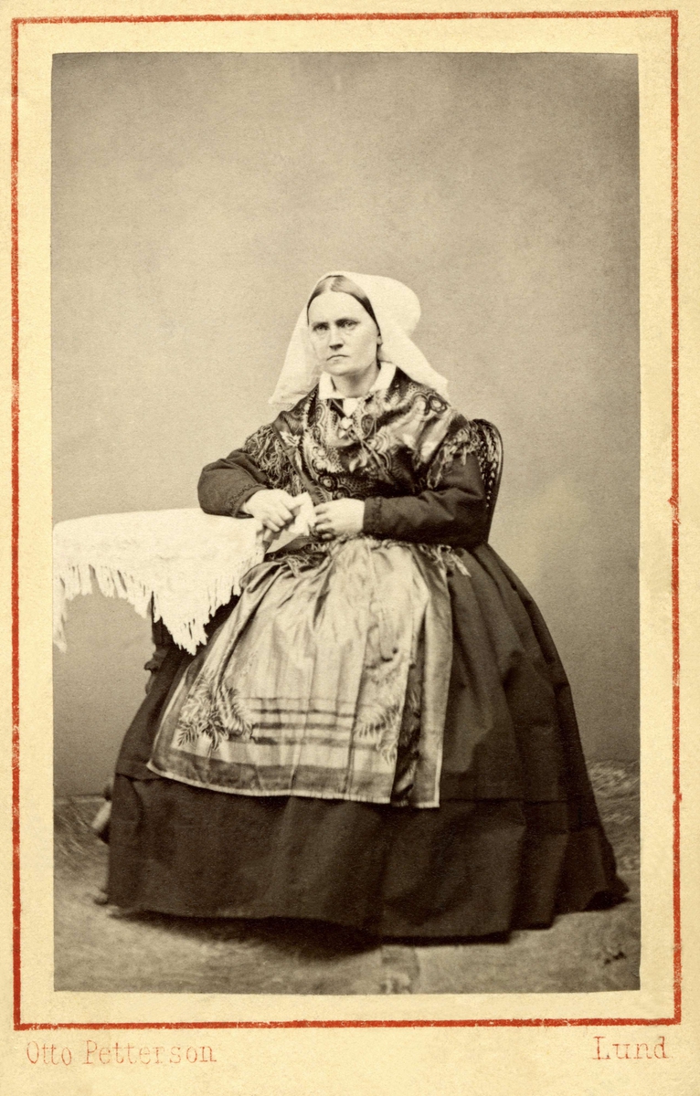 En kvinna poserar i en dräkt med huvudbonad till