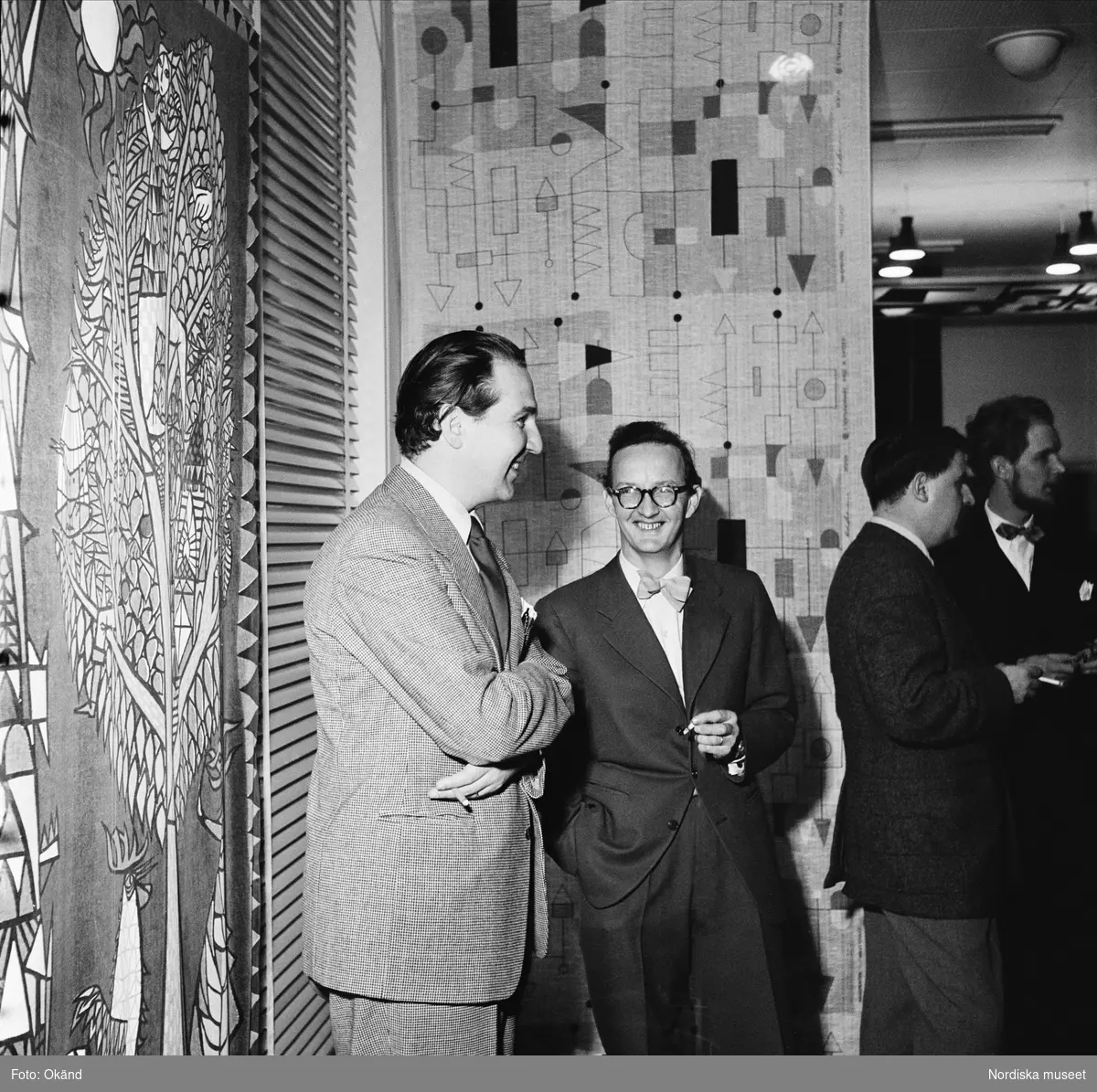 NK, utställningen Signerad textil har vernissage 29 oktober 1954. Från vänster Karl Axel Pehrson, Stig Lindberg, Olle Baertling och Olle Bonniér. I bakgrunden tyger som de har formgivit.