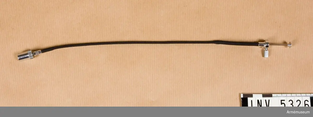 Trådutlösare M 1683-037.Trådutlösare med den gänga som passar för äldre Leicakamerors utlösare. Längd 190 mm, maxdiameter inklusive stoppskruv 21 mm. Textilstrumpan är svart, metalldelar är blankförkromade.