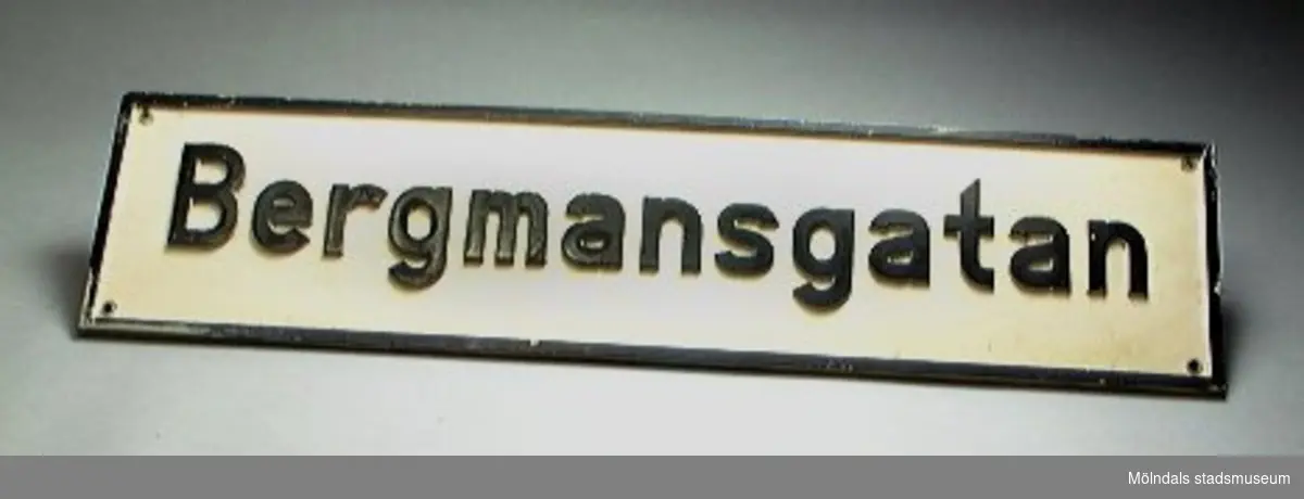 Vit med svart ram och upphöjd svart text: "Bergmansgatan".