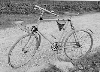 Cykel med ram, stänkskärmar och pakethållare fram. Cykeln är försedd med ringklocka och frambroms. Till cykeln finns ett verktygsväska i läder att fästa på ramen. Väskan är trasig och lädret sprött.

Cyklar av denna typ upphandlades av Postverket första gången 28/9 1894.

I Velocipedintruktion från 1910 nämns tillbehören: ringklocka, lykta, luftpump, skuvnyckel, oljekanna och verktygsväska. Skruvnyckeln ska förvaras i verktygsväskan och kannan i stallet eller på postkontoret.