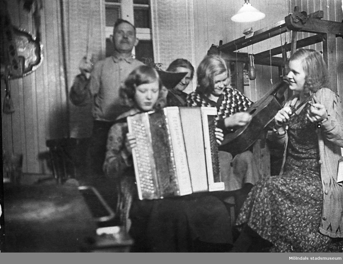 Familjen Hansson spelar och sjunger i köket år 1932. Hjalmar Hansson (1880-1970) arbetade på Papyrus.

"Familjen Hansson är samlad i farmors kök på Nybyggaregatan 21 på Kikås. Här är min söta och snälla Mamma Karin som försöker spela dragspel. Hon kunde inte utan bara poserade. Min älskade mor föddes 1913 och dog 1992. Farfar Hjalmar försöker vara dirigent. Min rekorderliga farmor Berta skymtar tyvärr bara bakom. Min faster Märta knäpper på en gitarr och faster Brita spelar på något instrument eller bara låtsas. Det är svårt att se."  (Berättat av Hans Hansson)
