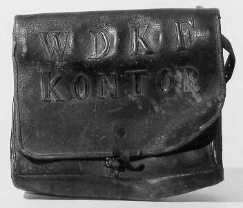 Landsvägspostväska av läder med bärrem och låsinrättning.
Försedd med klaff på vilken bokstäver i utskuret läder bildar: WDKF
KONTOR.

Låstenen med hänglås ligger löst.