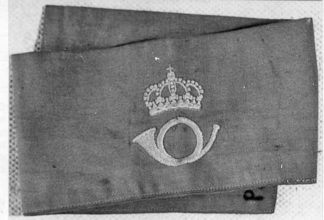Armbindel av ljusblått bomullstyg med postemblem, posthorn
under kunglig krona i gult.