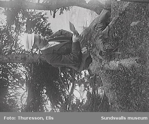Gunnar Häggbom på en stubbe på Norra berget, läsandes ett brev. I bakgrunden skymtar Sundsvall.