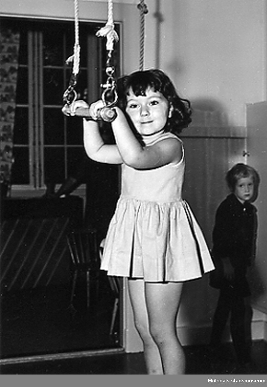 En flicka som leker med en trapets hängande från taket vid Holtermanska daghemmet 1953.