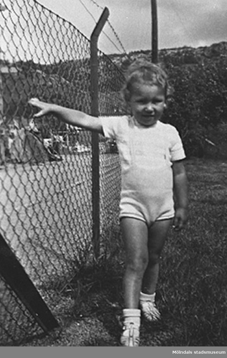 Håkan Carlsson står vid ett staket vid Krokslätts daghem, Dalhemsgatan 7 i Krokslätt. 
Under Margit Emilssons (gift Wannerberg -52) praktik som biträde
1945-10-01 - 1946-08-01.