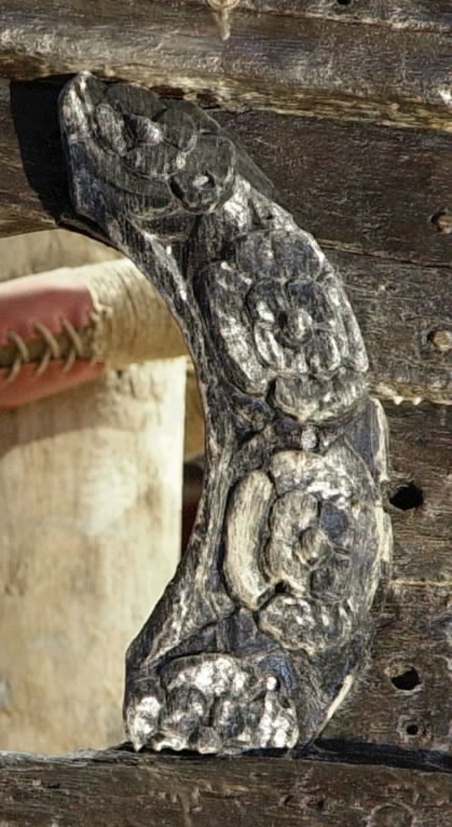 Bågformat parti av en skulpterad kanonportsring. Ringen har i sin helhet varit dekorerad med stora, utbredda blommor med omgivande foderblad, erinrande om s.k. tudorrosor. Dekoren har täckt hela ovansidan så när som på ett smalt, odekorerat fält utmed insidans kant. Baksidan är slät.
Skulpturdelen är välbevarad.

Text in English: A bow-shaped section of a carved wreath to a circular gun-port. The wreath is decorated with large open flowers with surrounding calyx-leaves, which are reminiscent of the so-called Tudor Rose. The decoration covers the whole upperside except for a narrow undecorated field along the inner edge. The back is smooth.
The sculpture is well preserved.